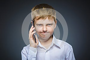 Portrait of offense boy with mobile or cell phone. Negative human emotion