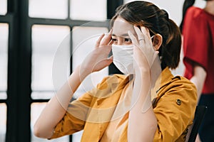 Portrait of office woman touching her head feeling unwell and get fever at the office, one of the symptoms of coronavirus Covid