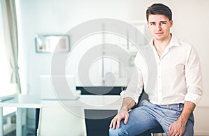 Portrait of office worker man sitting at office desk using laptop computer