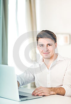 Portrait of office worker man sitting at office desk using laptop computer