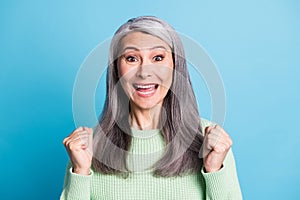 Portrait ofi amazed beautiful celebrating woman raise fists wear casual isolated on blue color background photo