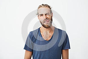 Portrait og beautiful young man with stylish hair and beard making funny and silly faces while his girlfriend tries to