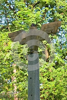 A portrait of an old, bird shaped, outdoor, cement lighting post, with a wide wing span, located in a Thai public park.