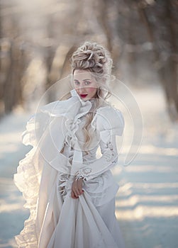 Portrait of an old-fashioned blonde woman in a vintage white dress in a winter forest. A girl with a high, old-fashioned