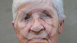 Portrait of old grandmother with a sad sight. Wrinkled face of elderly lady looking into camera. Sorrow facial