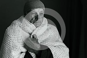 Portrait of old man wrapped in blanket and warm clothes feeling cold in house without heat, pensioner feels cold and