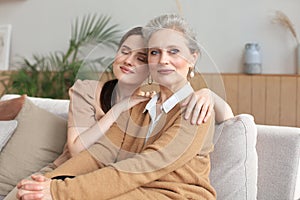 Portrait of old mother and mature daughter hugging at home. Happy senior mom and adult daughter embracing with love