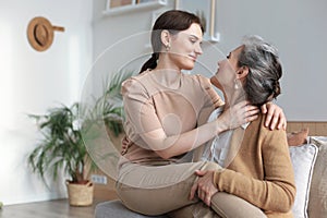 Portrait of old mother and mature daughter hugging at home. Happy trusted relations. Family concept