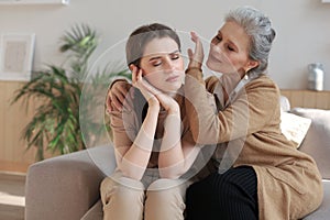 Portrait of old mother and mature daughter hugging at home. Happy trusted relations. Family concept