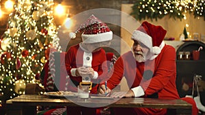 Portrait of old parent and child writing letter to Santa Claus. Christmas helper reading wish list. Grandfather with