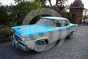 Old retro blue commander vintage car parked at driveway of a house, outdoor natural background, vintage car