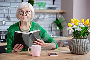 Portrait of older adult female sitting at table with Bible