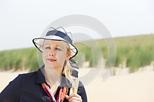 Portrait of an older woman standing at the beach with hat