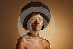 Portrait of one beautiful african american woman with an afro and flawless skin posing topless in a studio. Powerful