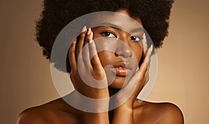 Portrait of one beautiful african american woman with afro posing in a studio and touching her face with her hand