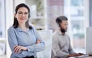 Portrait of one confident young caucasian woman standing with arms crossed while working in a call centre with her