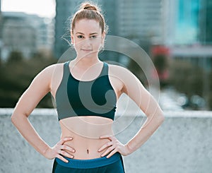 Portrait of one confident young caucasian woman standing with hands on hips ready for exercise outdoors. Determined