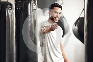 Portrait of one fit young hispanic man pointing forward with his finger while exercising in a gym. Happy mixed race