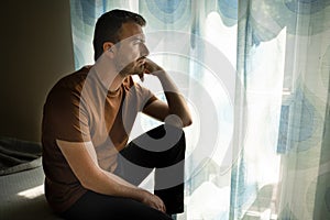 Portrait of one guy feeling sad and looking through window