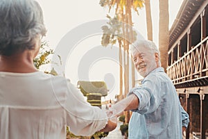 Portrait of one happy and cute senior holding hand of old pensioner wife walking and visiting new places together with the sunset