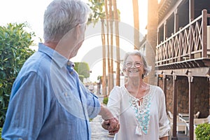 Portrait of one happy and cute senior holding hand of old pensioner wife walking and visiting new places together with the sunset