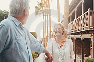 Portrait of one happy and cute senior holding hand of old pensioner wife walking and visiting new places together with the sunset