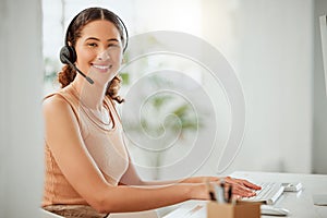 Portrait of one happy young hispanic female call centre telemarketing agent talking on a headset while working on a