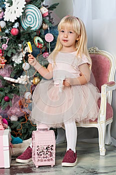 Portrait of one little Caucasian cute blonde girl with colored lollipops in the festive New year studio room