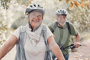 Portrait of one old woman smiling and enjoying nature outdoors riding bike with her husband laughing. Headshot of mature female