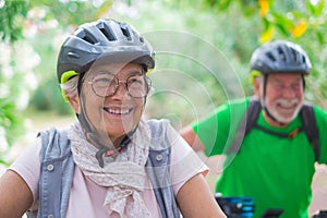 Portrait of one old woman smiling and enjoying nature outdoors riding bike with her husband laughing. Headshot of mature female