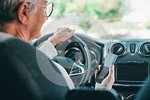 Portrait of one old woman using phone in car while driving in the road risk causing an accident. Close up of hands holding