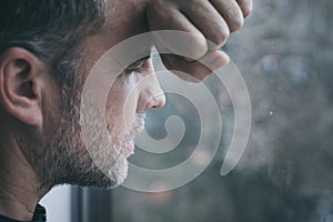 Portrait one sad man standing near a window