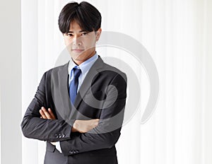 Portrait one young asian businessman who smart and handsome wearing black suit standing look at camera while smiling and folded