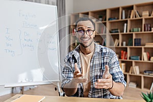 Portrait of online teacher man speaking by webcam and explaining english grammar rules for students