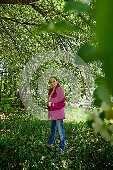 Portrait of a ordinary cute girl in the green park full of blossoming apple tree with white flower in a springtime