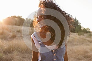 Portrait outdoors of a beautiful young afro american woman smiling at sunset. Yellow background. Lifestyle