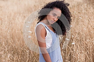 Portrait outdoors of a beautiful young afro american woman at sunset. Yellow background. Lifestyle