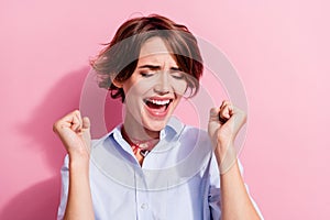 Portrait of overjoyed cheerful girl closed eyes raise fists scream yes accomplish isolated on pink color background