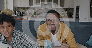 Portrait of overjoyed family dad and child watching soccer on TV in apartment cheering enjoying game