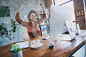 Portrait of overjoyed realtor lady sit chair raise fists successful sale monitor desk workplace indoors