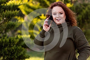 Portrait of overweight woman calling on the phone walking at the park. The concept of business and freelancing