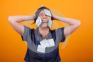 Portrait of overwhelmed business woman with work in studio over yellow background