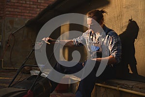 Portrait of an overworked gardener in blue overalls with a lawn mower in the garden at sunset after a hard day's