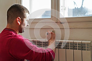 Portrait of painter young man in red t-shirt painting the wall in white color, with paint roller brush, home decor