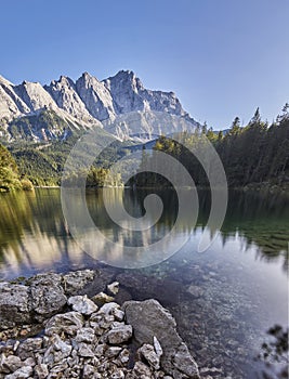 Portrait panorama of the crystal clear water of the Eibsee with the Zugspitze mountain including reflection in the background