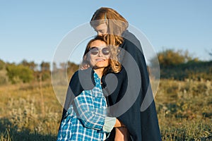 Portrait of parent and child. Happy mother and little daughter hugging together. Nature background, rural landscape, green meadow