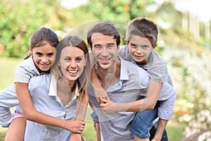 Portrait of parents carrying children on their back outdoors