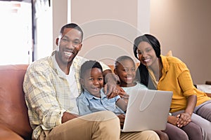 Portrait of parents and children holding laptop while sitting on sofa