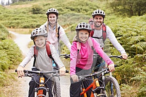 Portrait of parents and children sitting on mountain bikes in a country lane during a family camping trip, front view photo