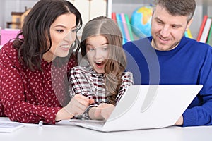 Portrait of parents and daughter using laptop in room photo